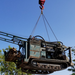 Drill rig being lifted in air by crane